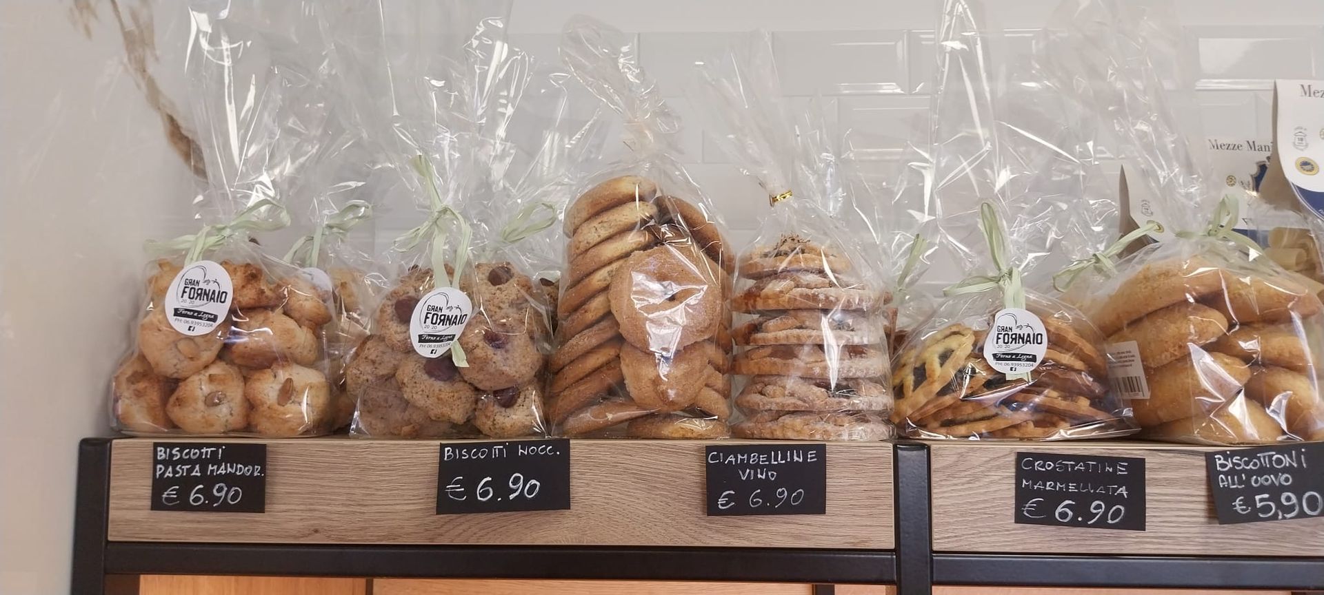 Un mucchio di sacchetti di biscotti sono appoggiati sullo scaffale di una panetteria.