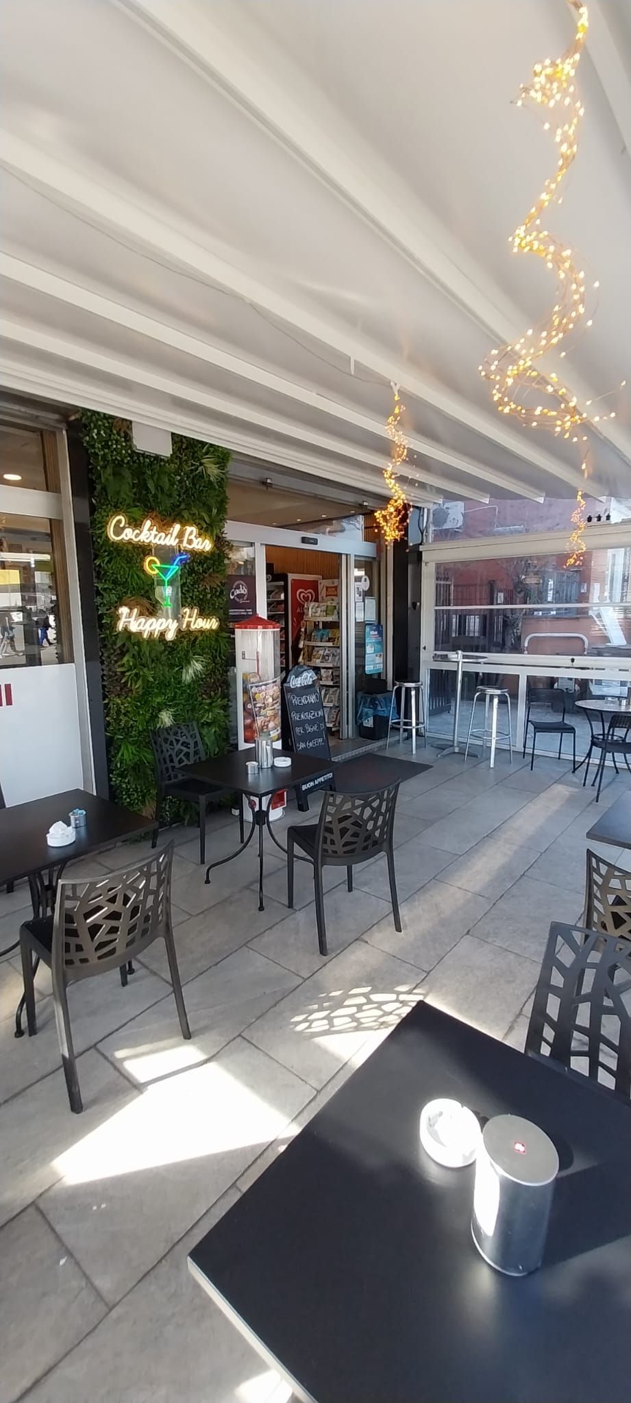 Un ristorante con tavoli e sedie all'esterno e un cartello con la scritta "Coca Cola".