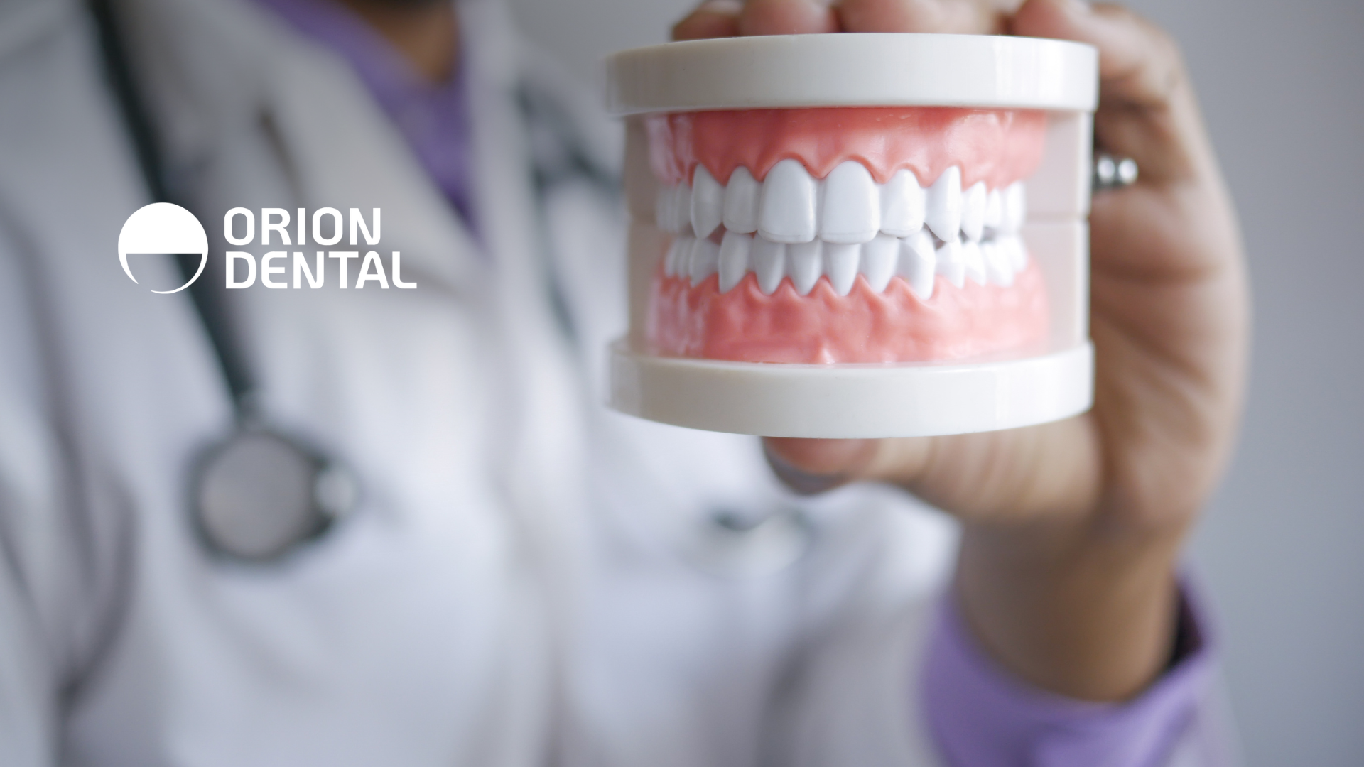 A dentist is holding a model of teeth in his hand.