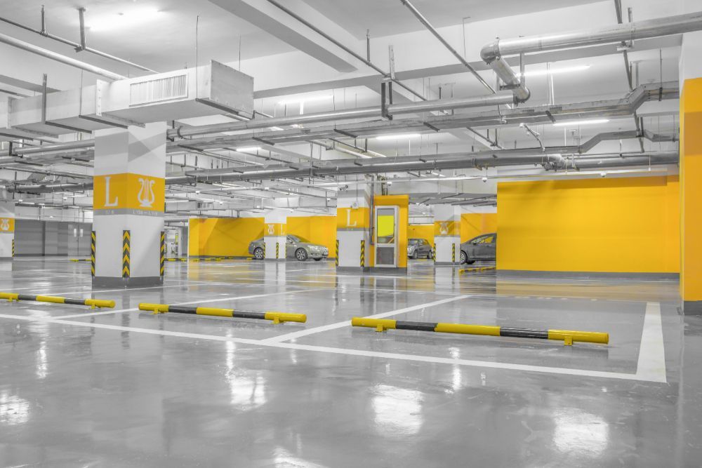 An empty underground parking garage with yellow walls and cars parked in it.