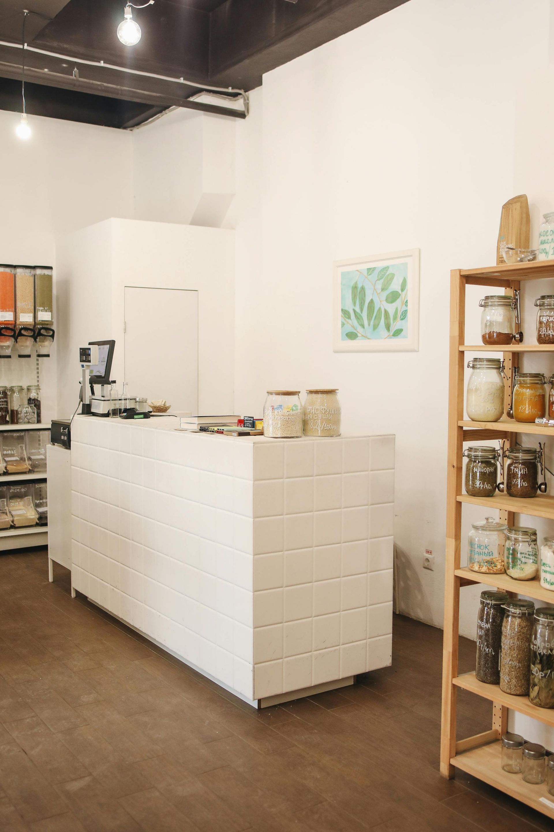 A kitchen with a counter and shelves filled with jars of food.