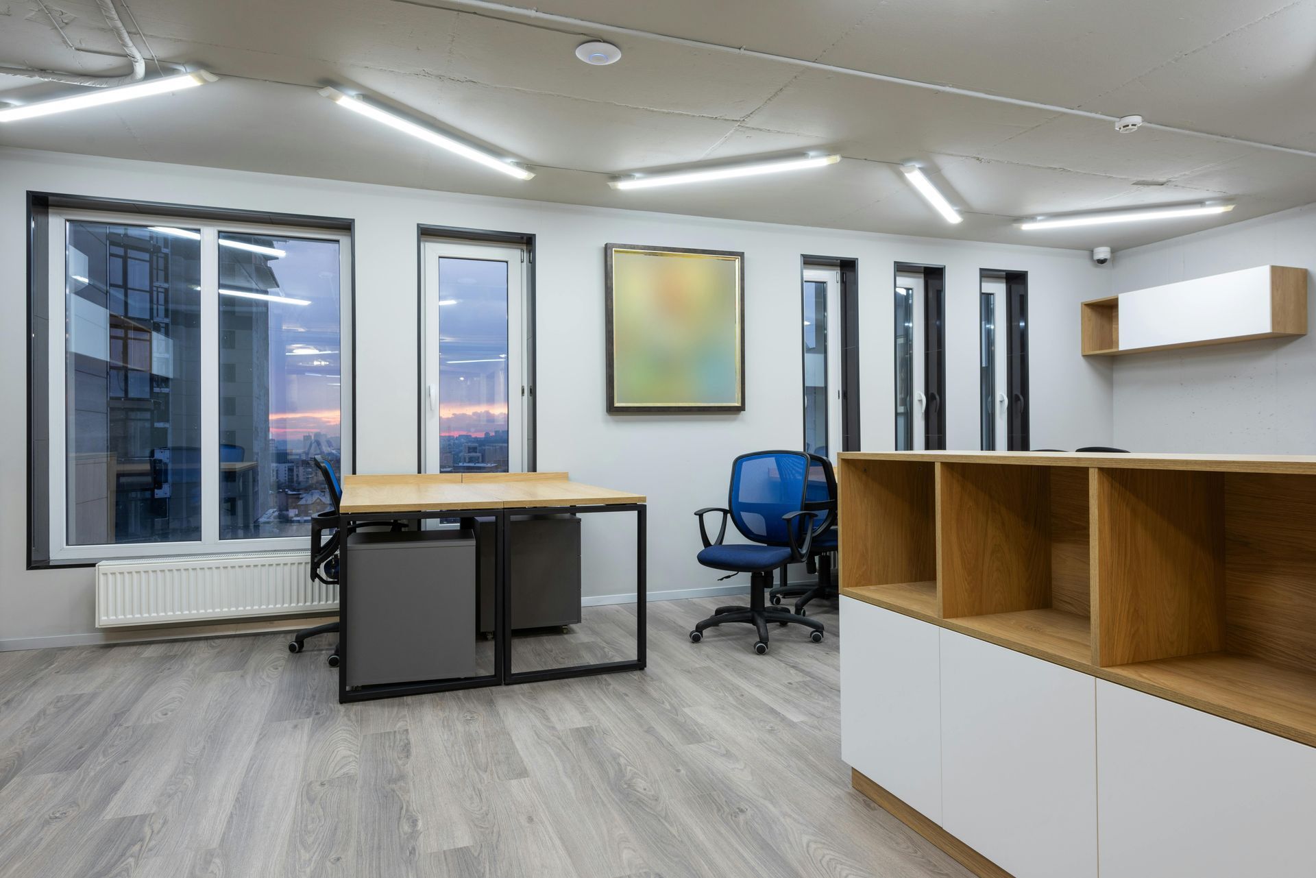 An empty office with a desk , chair , shelves and windows.