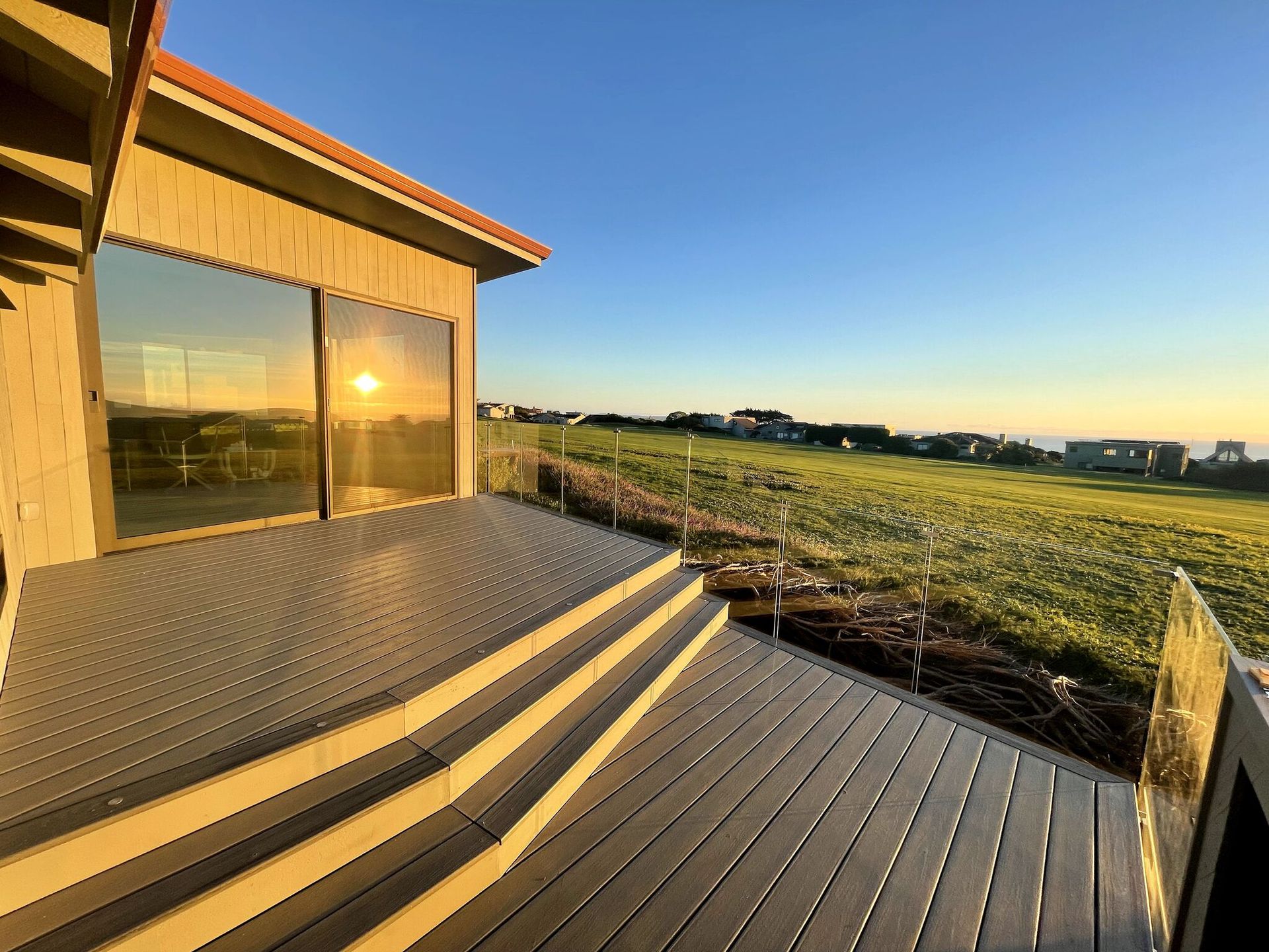 A deck with stairs leading up to a house with a view of a field.