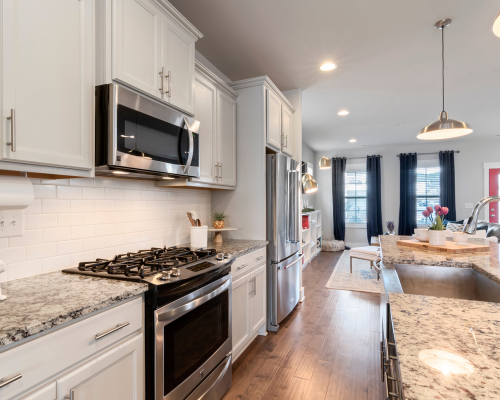 A kitchen with white cabinets , stainless steel appliances and granite counter tops.