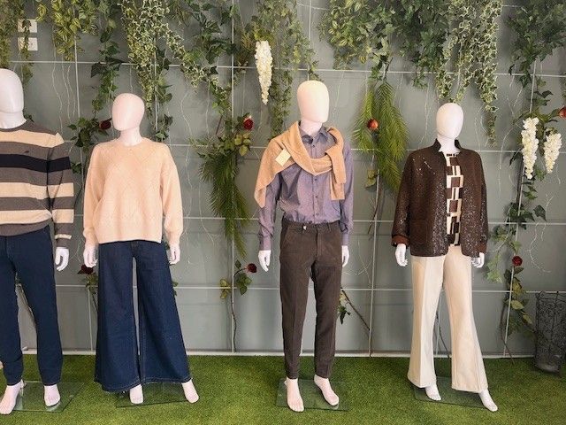 Quattro manichini vestiti su uno sfondo verde.