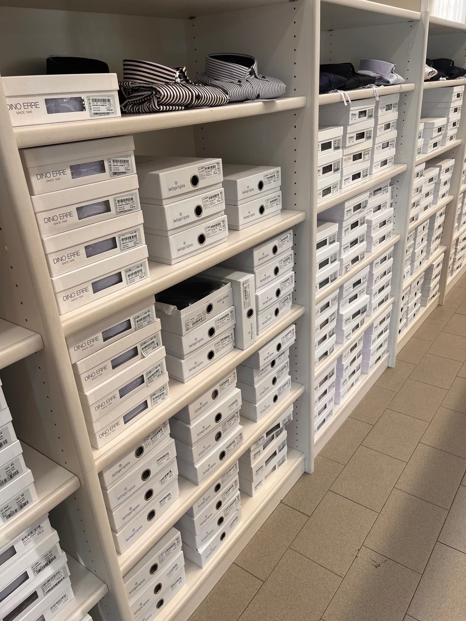 File di scatole bianche e camicie piegate sugli scaffali di un negozio al dettaglio.