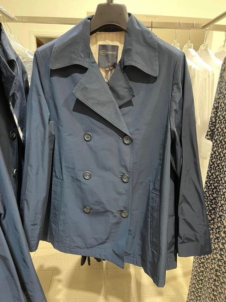 Giacca doppiopetto blu navy appesa a un attaccapanni in un negozio di abbigliamento.