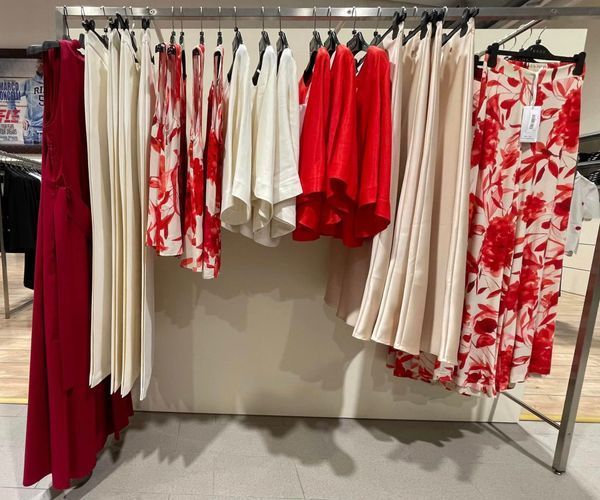 Appendiabiti con abiti con stampe rosse, bianche e floreali in un negozio.