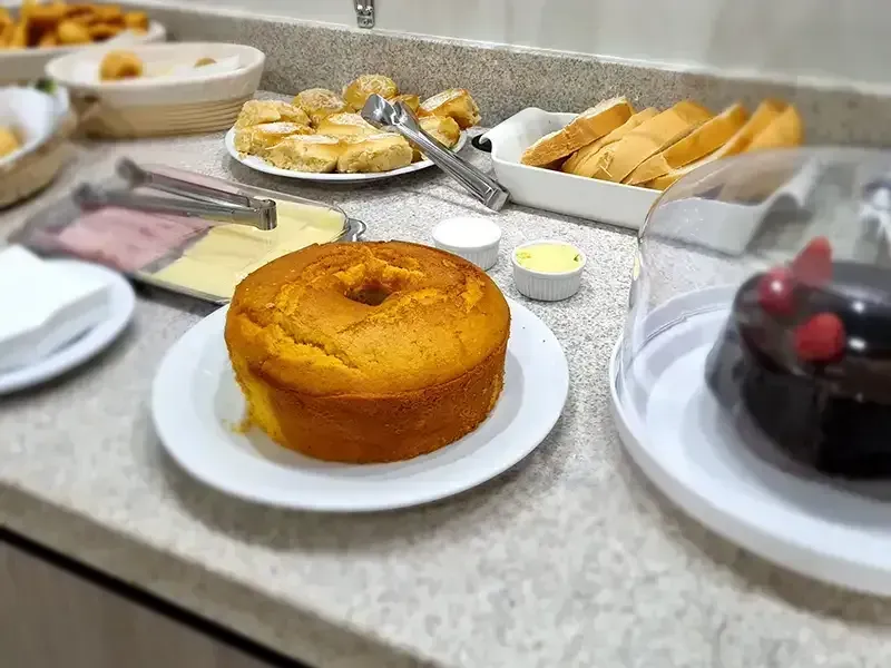 Buffet de café da manhã com bolo, pão e doces.