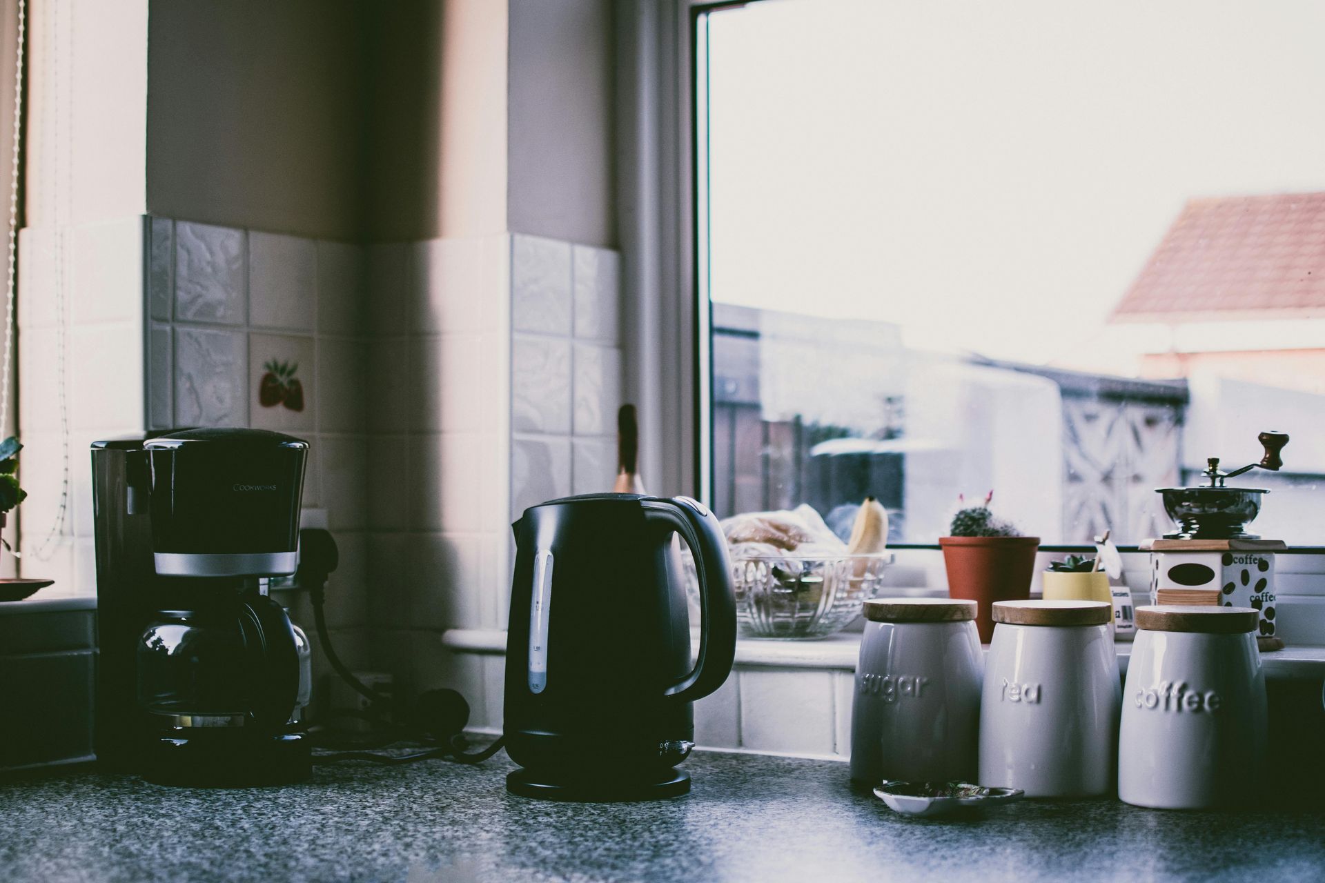A kitchen counter with a coffee maker , kettle , and canisters.