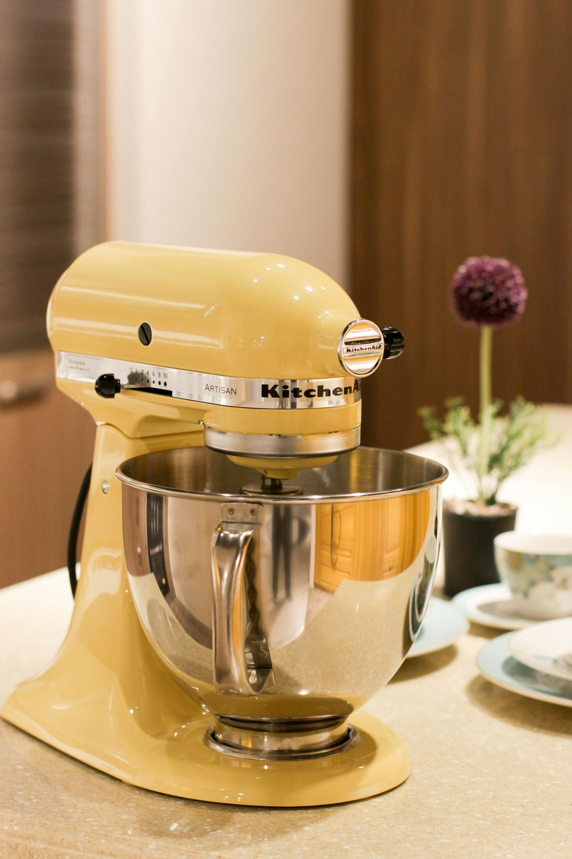 A yellow kitchenaid mixer is sitting on a counter.