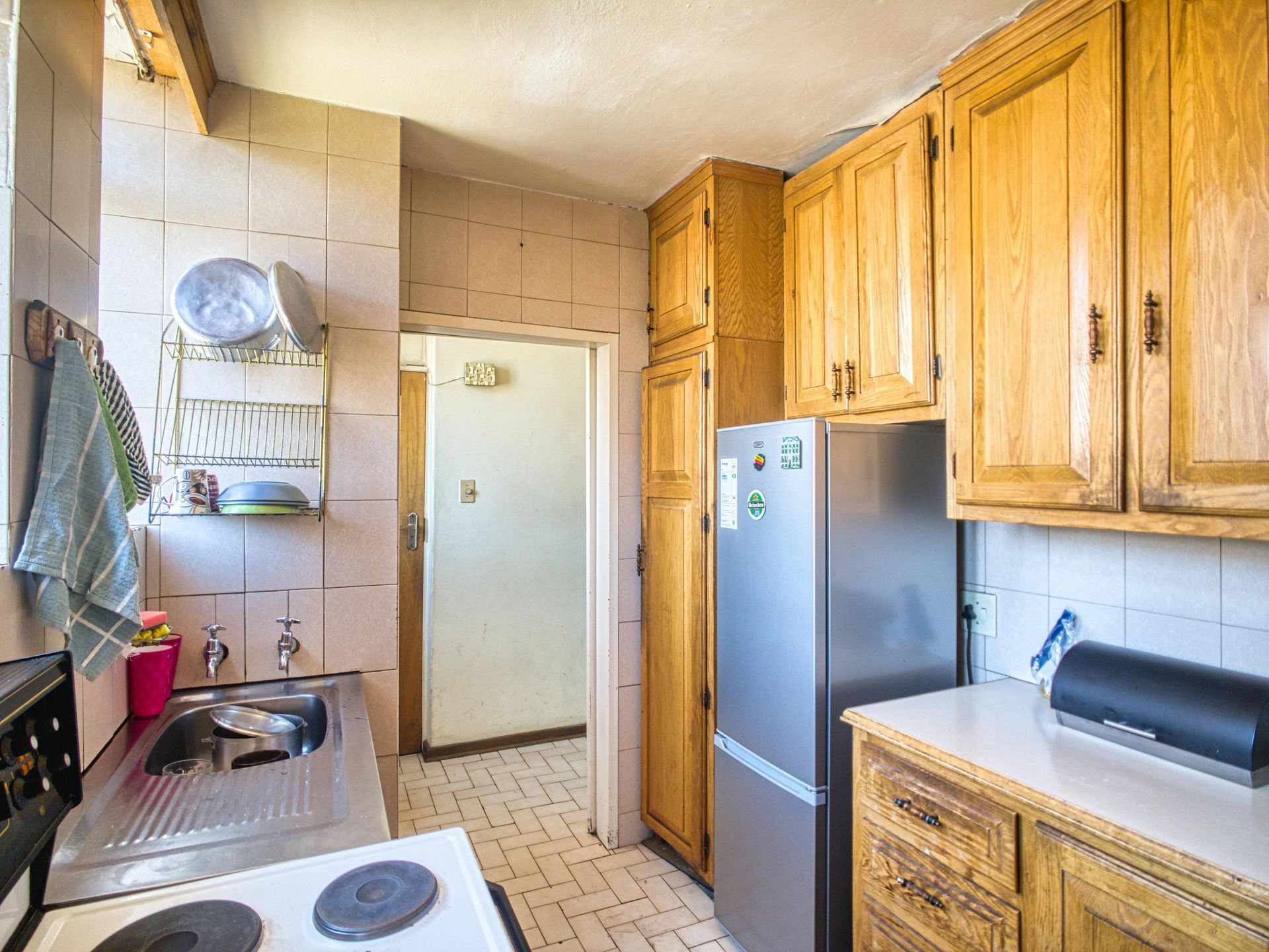 A kitchen with wooden cabinets , a stove , a refrigerator and a sink.