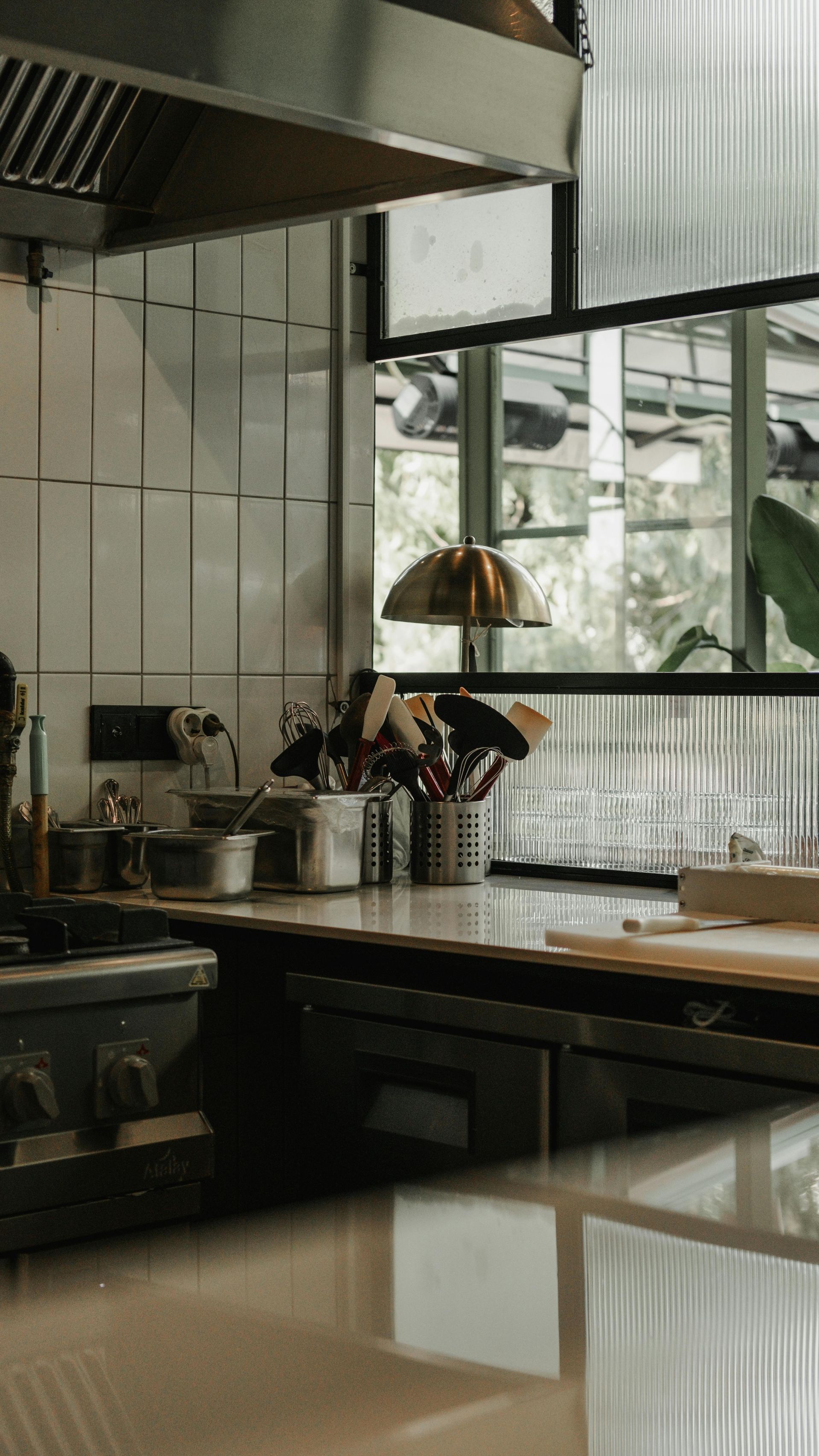 A kitchen with a lot of utensils on the counter and a large window.