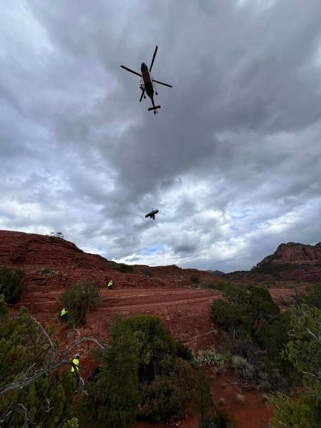 A DPS helicopter lifts an injured patient from the side of a mountain