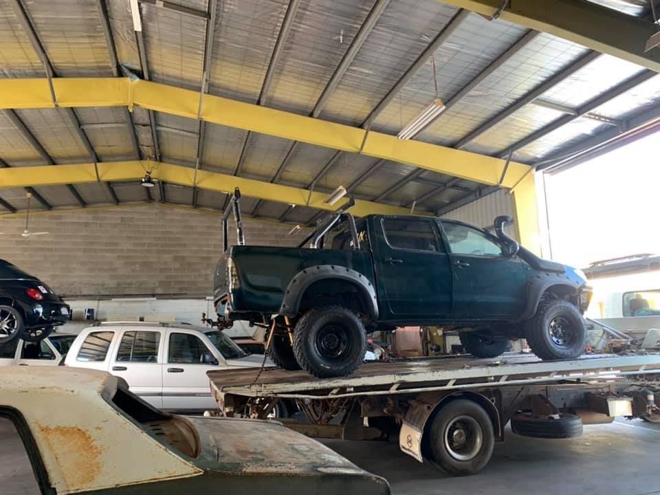 A Green Truck is Sitting on Top of a Flatbed Truck in a Garage — JDM Mechanical & Aircon Repairs In Coconut Grove, NT