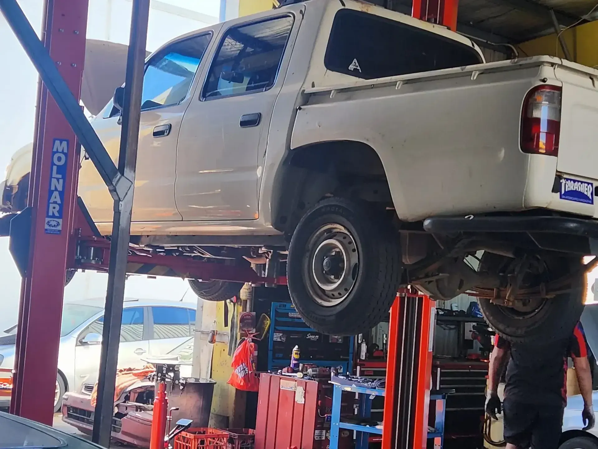 A White Truck is Sitting on a Lift in a Garage — JDM Mechanical & Aircon Repairs In Coconut Grove, NT