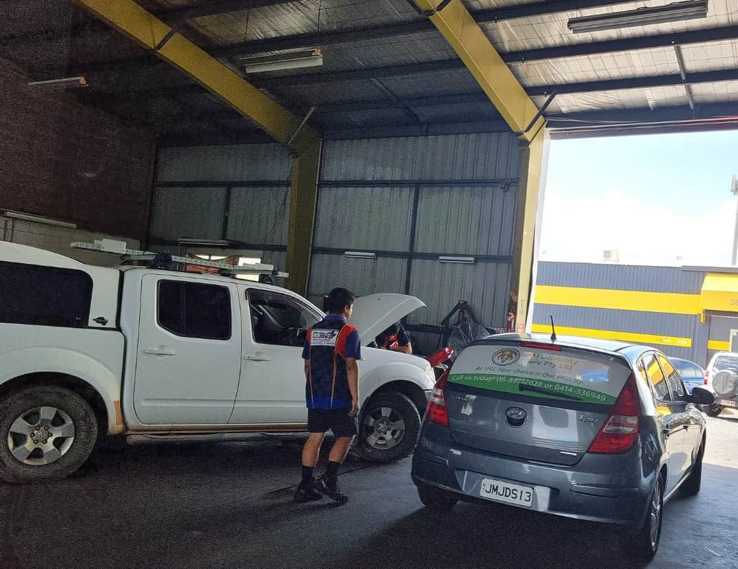 A Man is Standing Next to a Truck With the Hood Open — JDM Mechanical & Aircon Repairs In Coconut Grove, NT