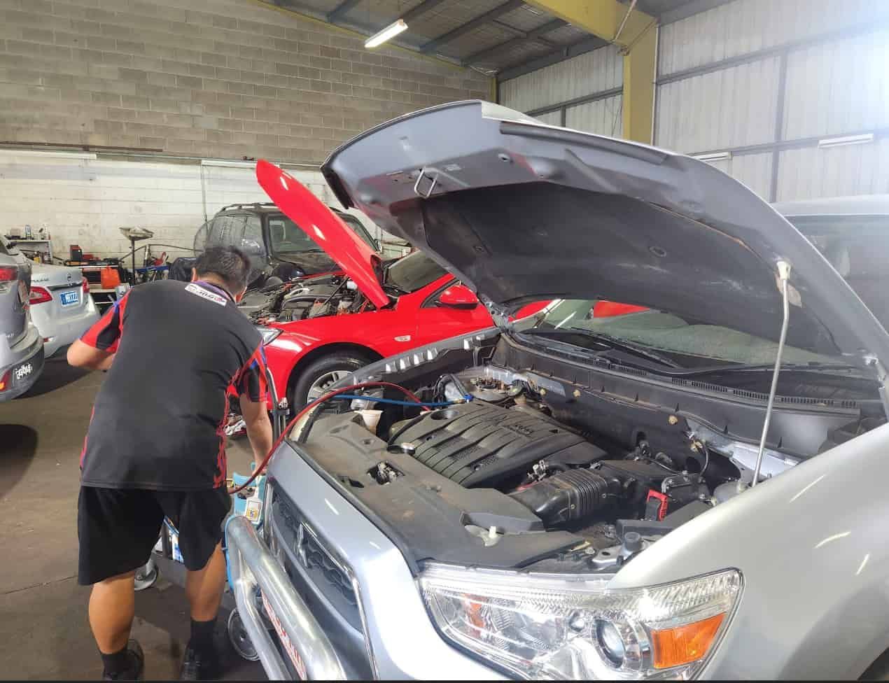 A Man is Working Under the Hood of a Car — JDM Mechanical & Aircon Repairs In Coconut Grove, NT