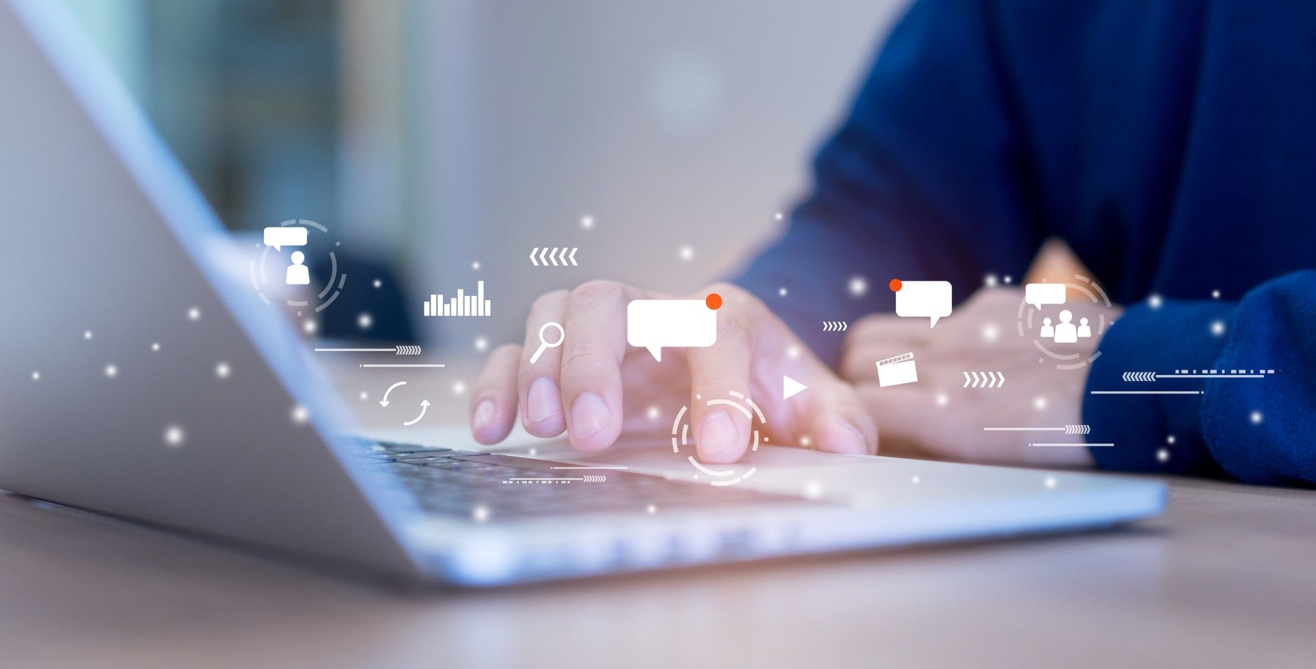 Person typing on laptop; floating icons above keyboard representing communication and data visualization.