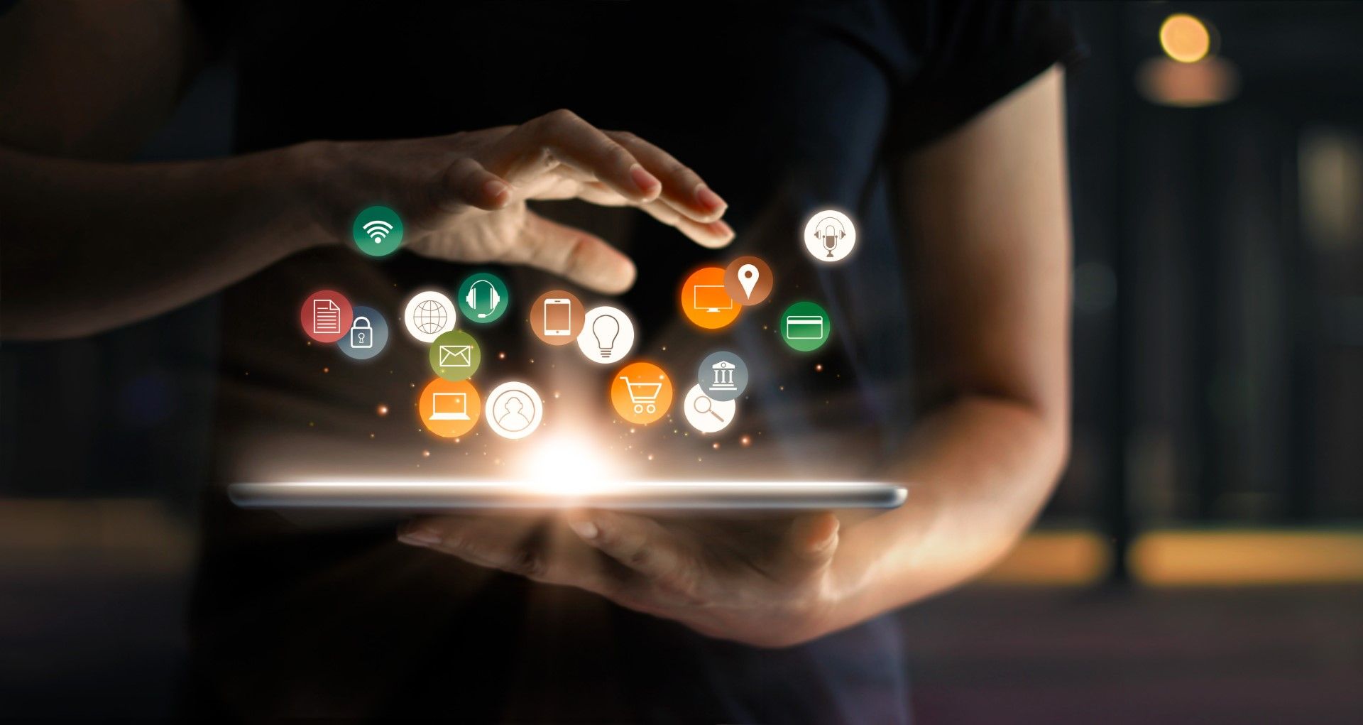 Person holding tablet with glowing interface icons.