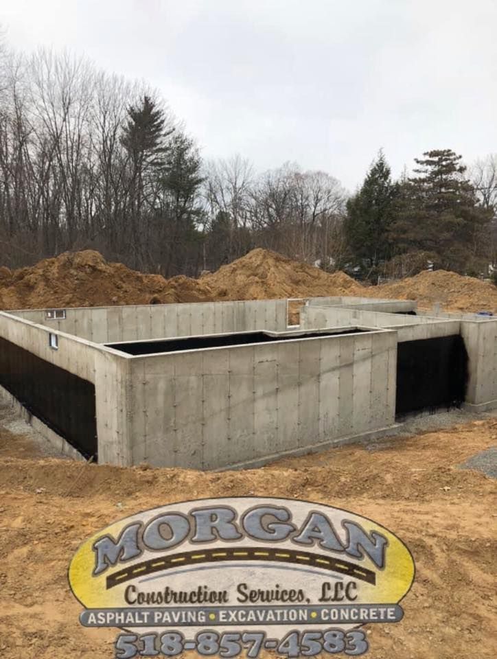Concrete foundation under construction, with Morgan Construction Services logo.