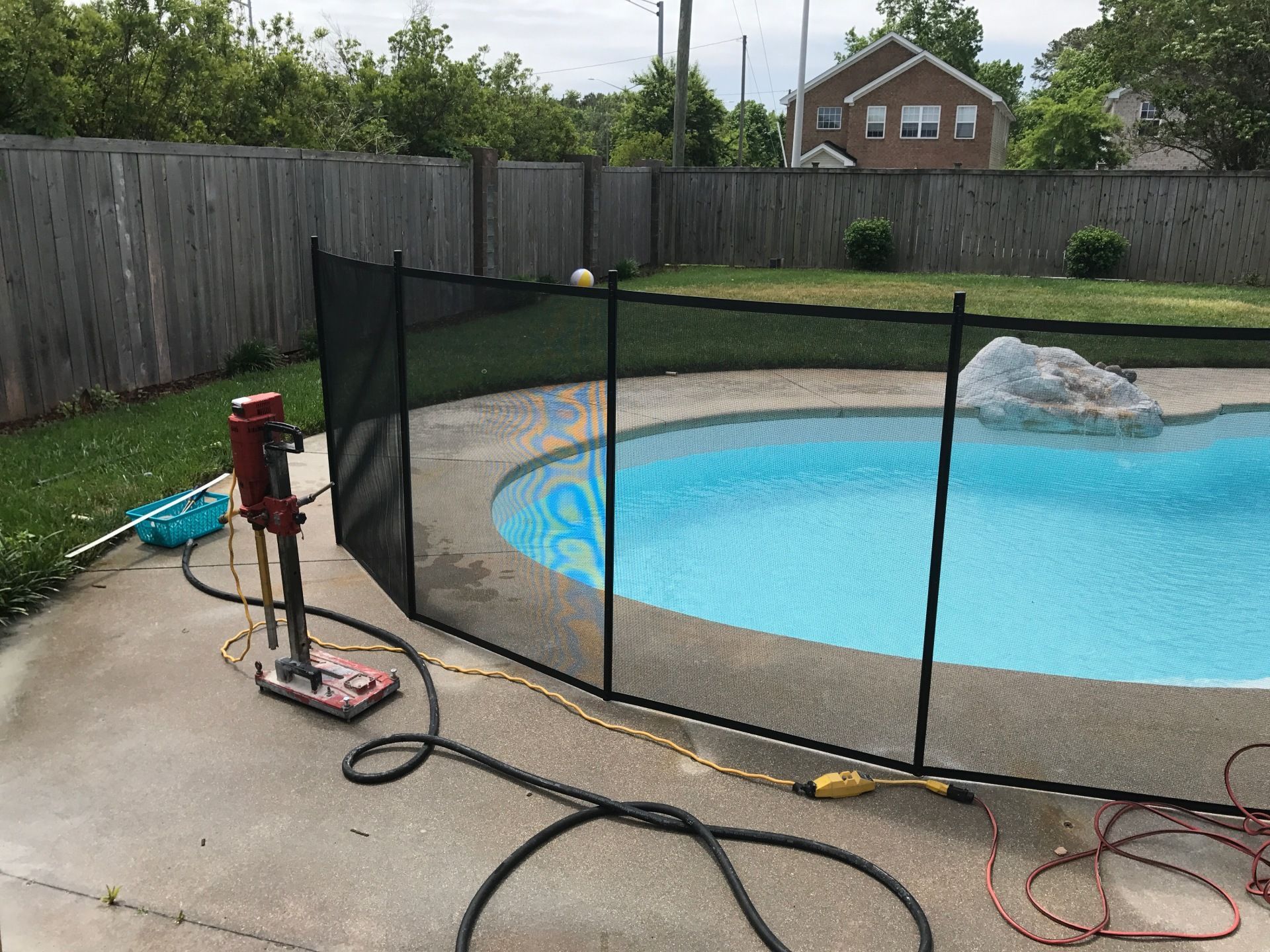 A fence around a swimming pool with a hose attached to it.