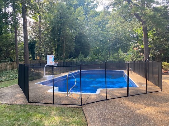 A swimming pool with a fence around it and trees in the background.