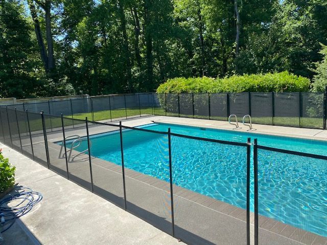 A large swimming pool surrounded by a fence and trees.