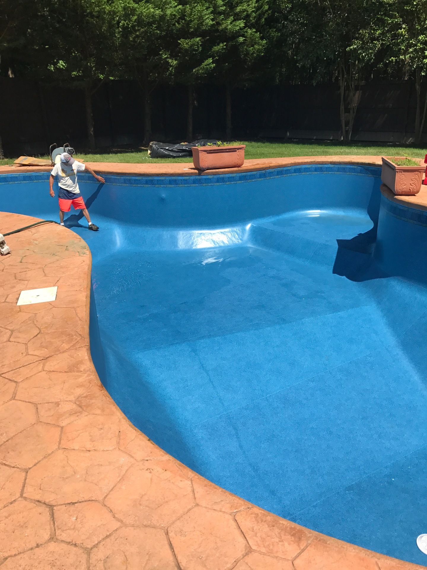 A man is cleaning a large blue swimming pool