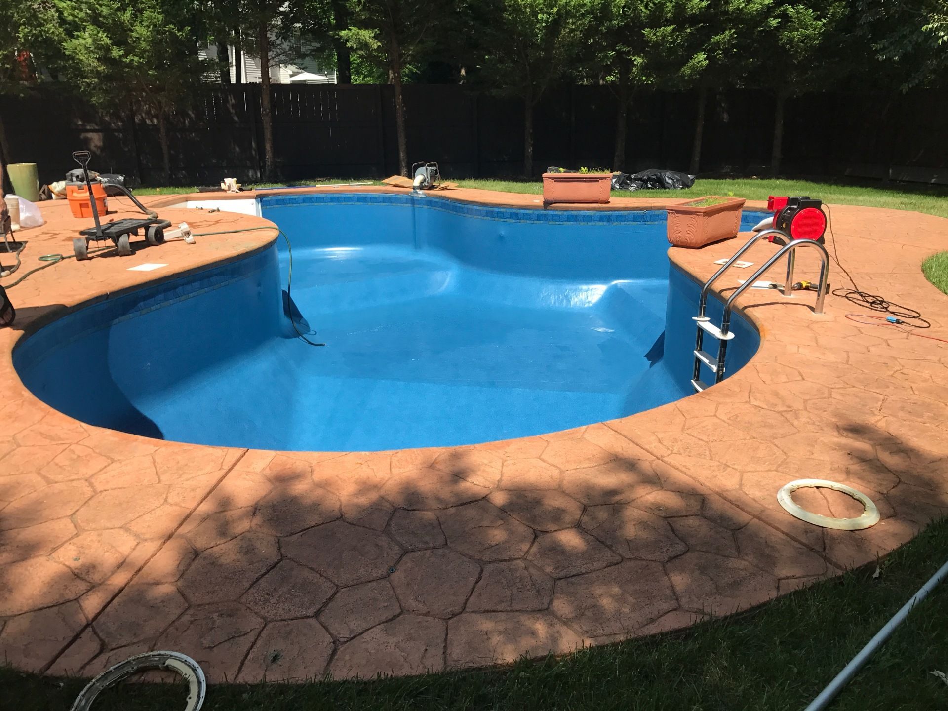A large blue swimming pool is being painted in a backyard.