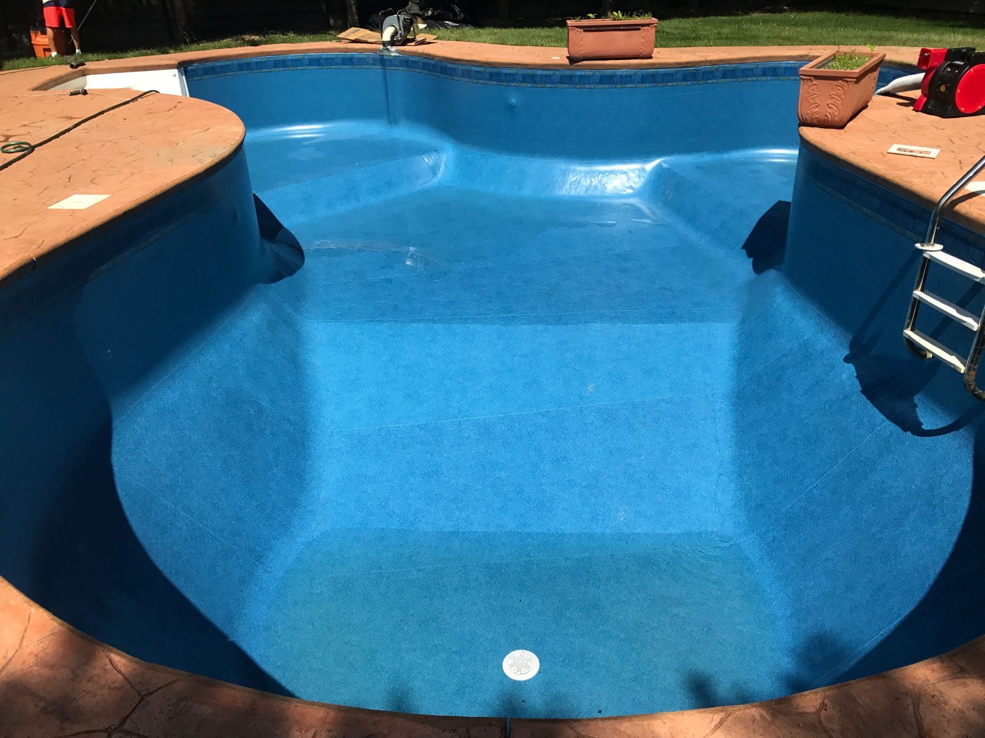 A large blue swimming pool with a ladder on the side of it.