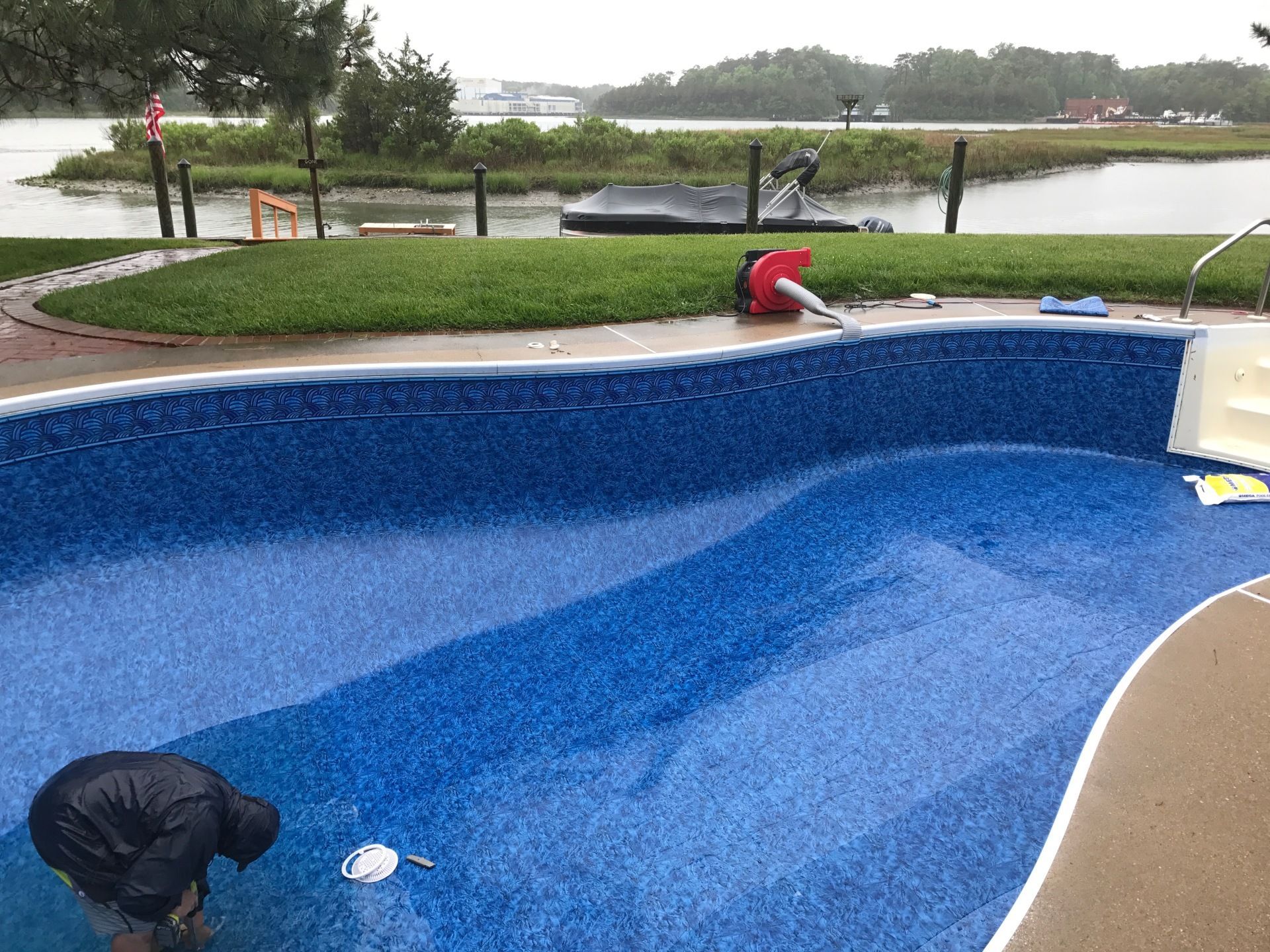 A man is working on a swimming pool in the rain.