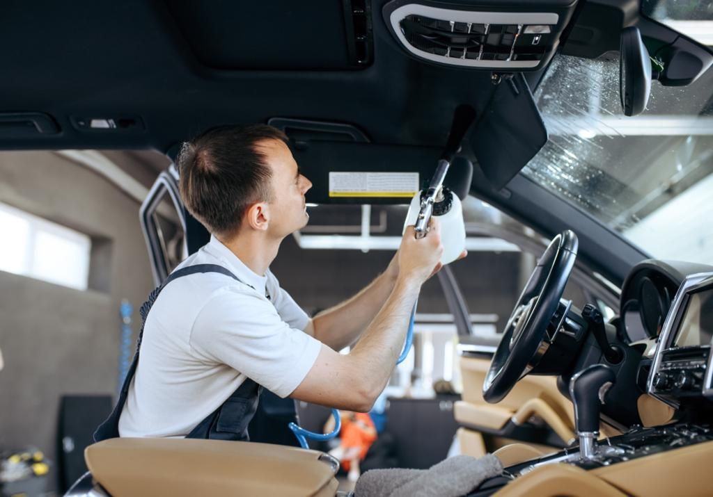 A man is cleaning the inside of a car with a cloth.