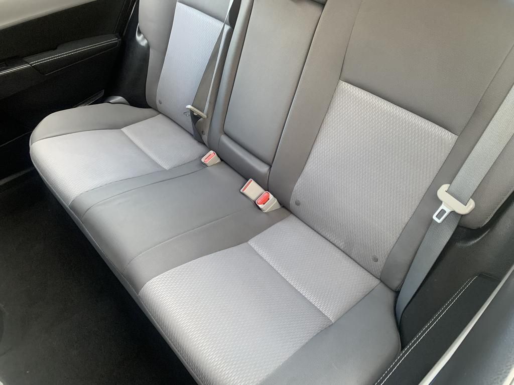 The back seat of a car with a seat belt on it.