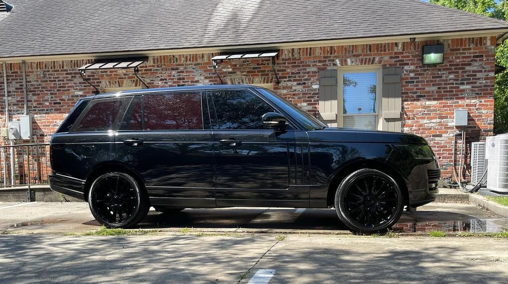 A black Range Rover is parked in front of a brick building.