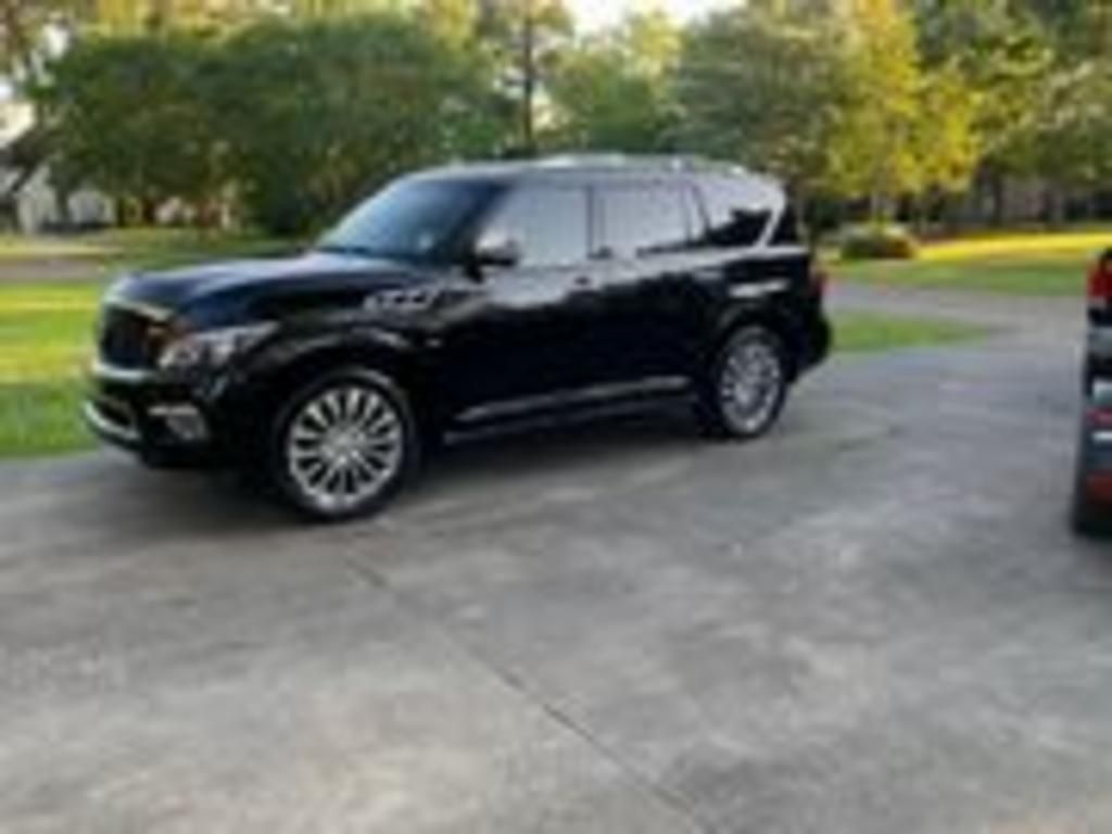 A black suv is parked in a driveway next to a red truck.