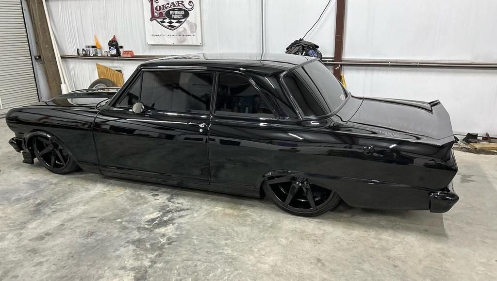 A black car is sitting on the ground in a garage.