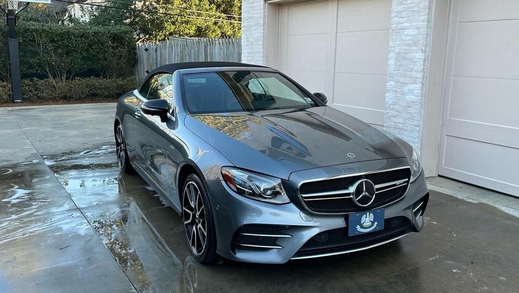 A mercedes benz e class convertible is parked in a driveway next to a garage.