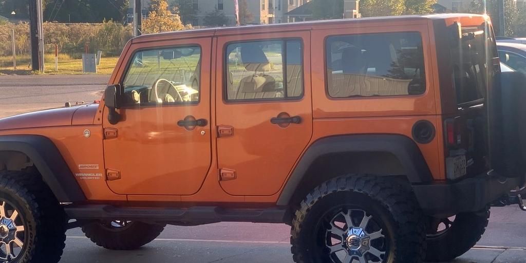 An orange jeep is parked in a parking lot.