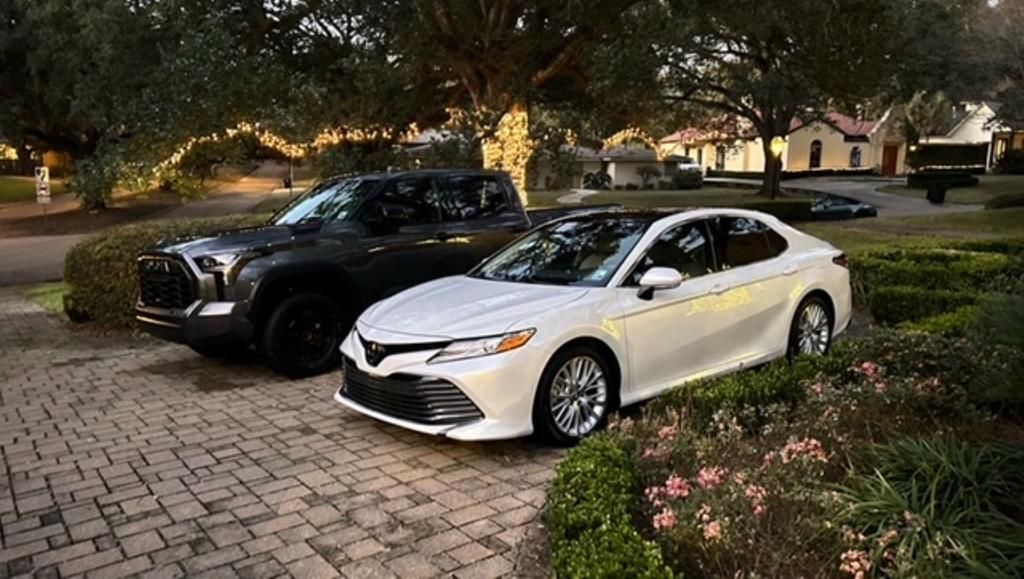Two cars are parked in a driveway next to each other.