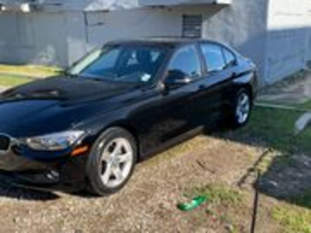 A black bmw 3 series is parked in front of a house.