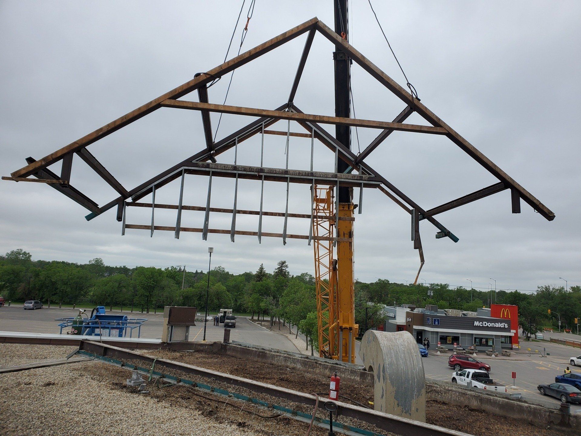 A large wooden structure is being lifted by a crane