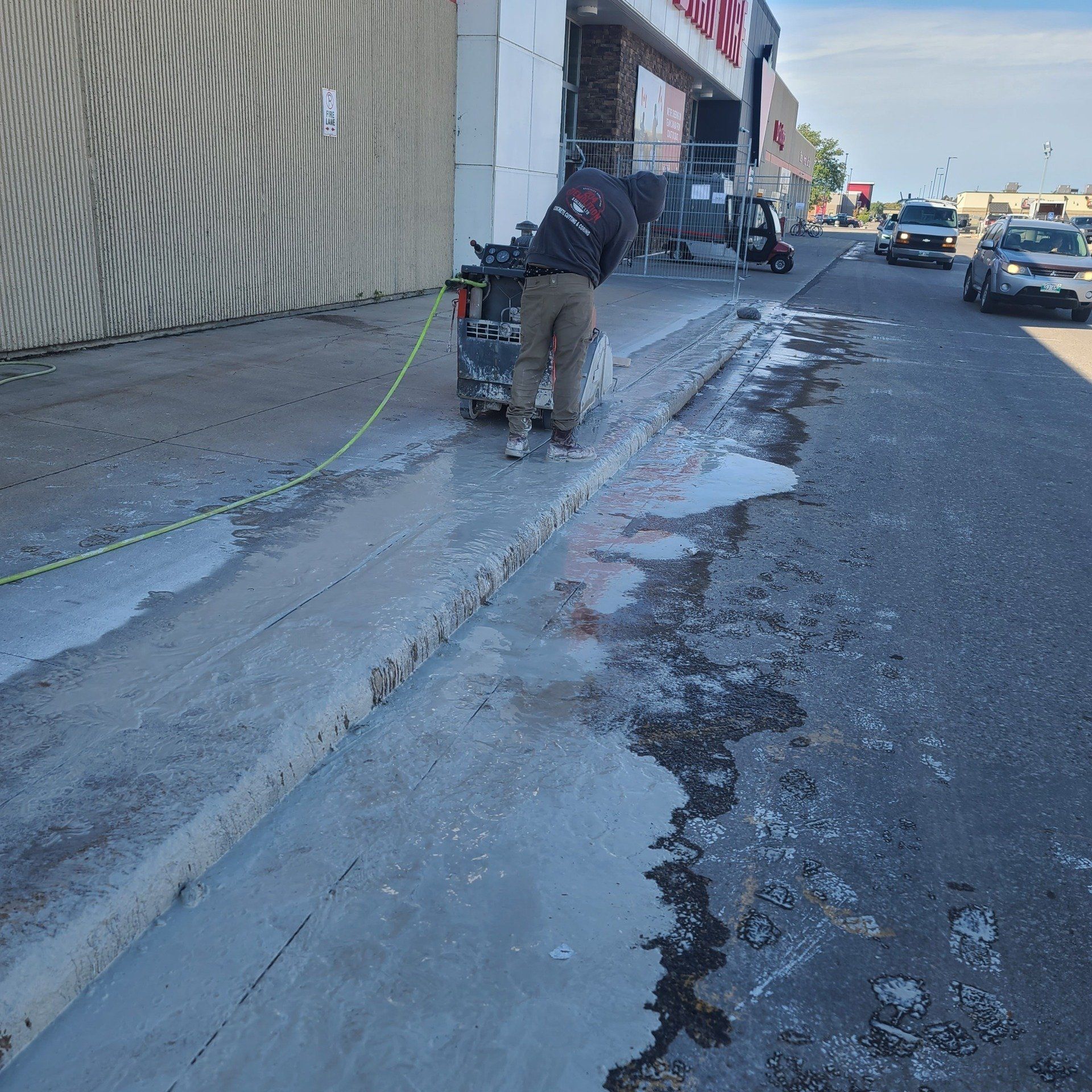 A man is cutting concrete on the side of the road