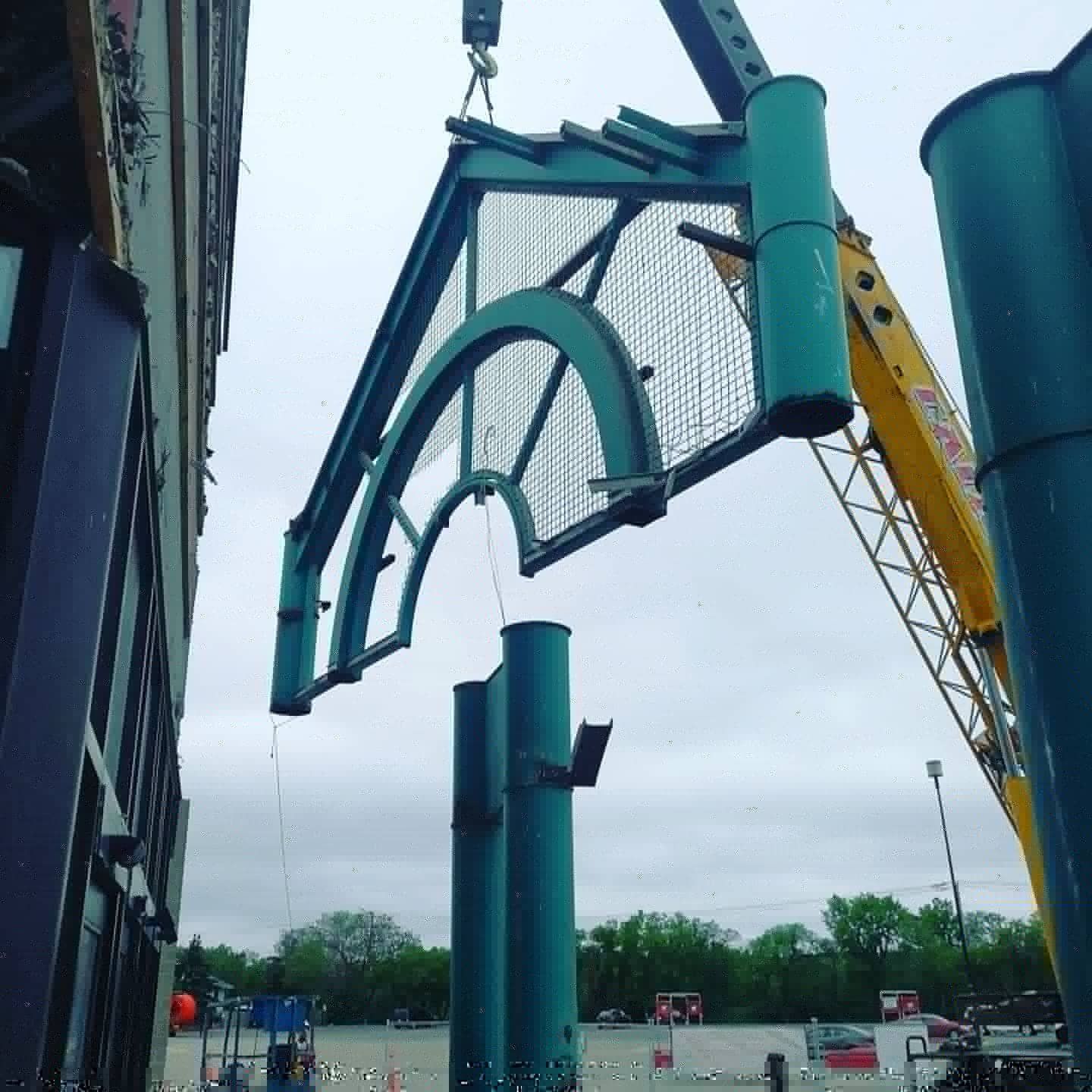 A crane is lifting a large piece of metal in front of a building