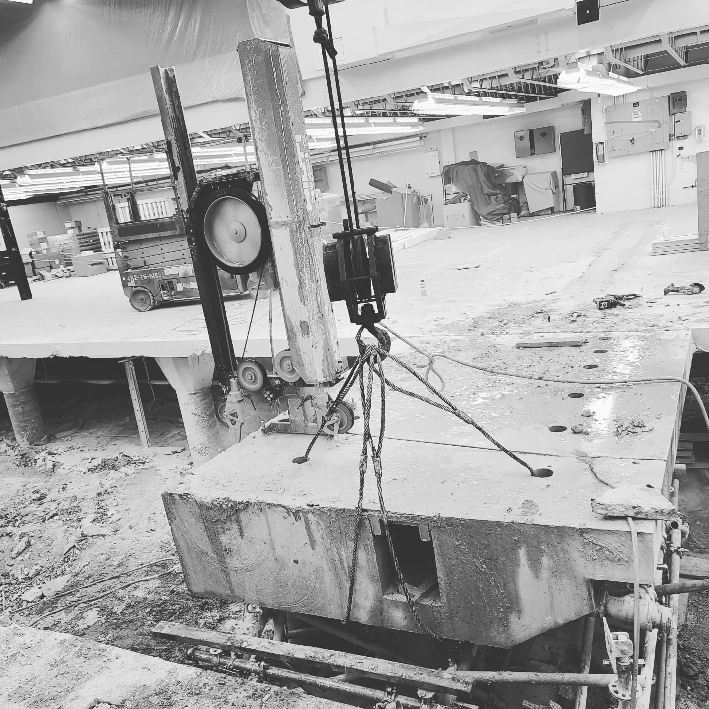 A large concrete block is being lifted by a crane