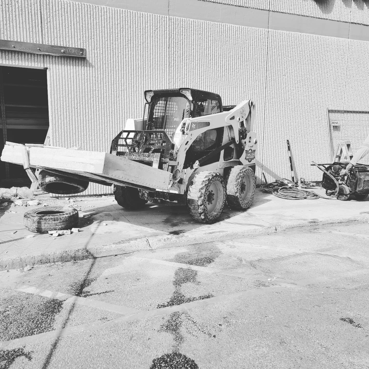 A black and white photo of a bulldozer parked in front of a building.