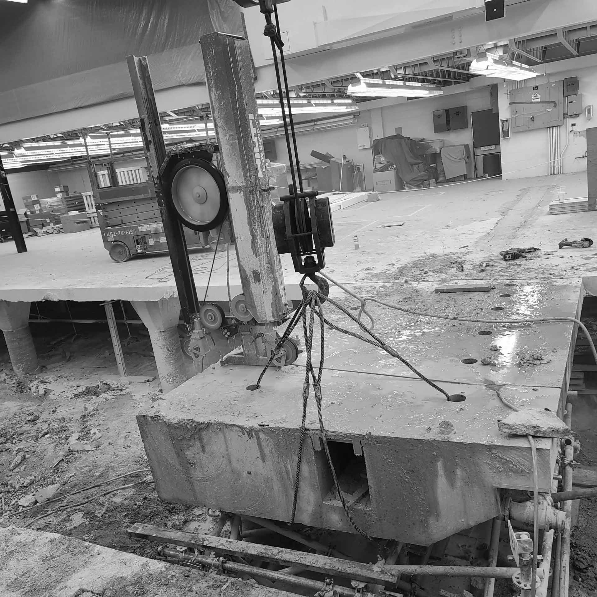A large concrete block is being lifted by a crane in a black and white photo