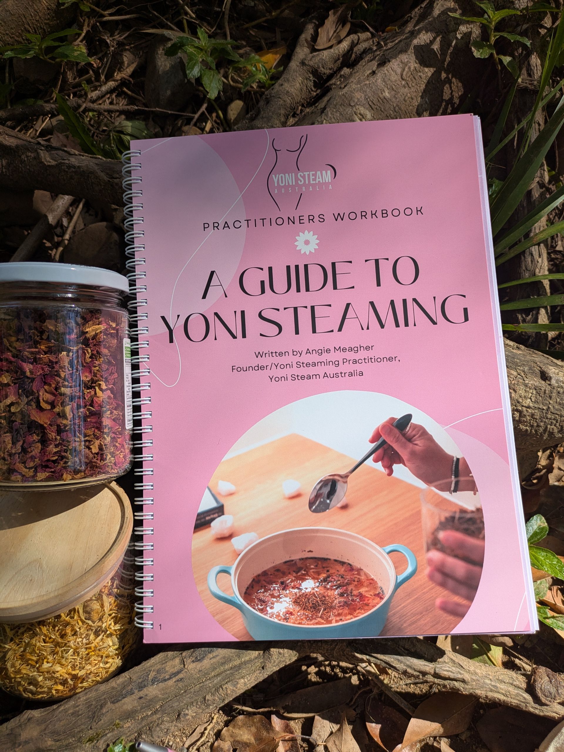 Book and herbs for yoni steaming. Pink book cover reads 