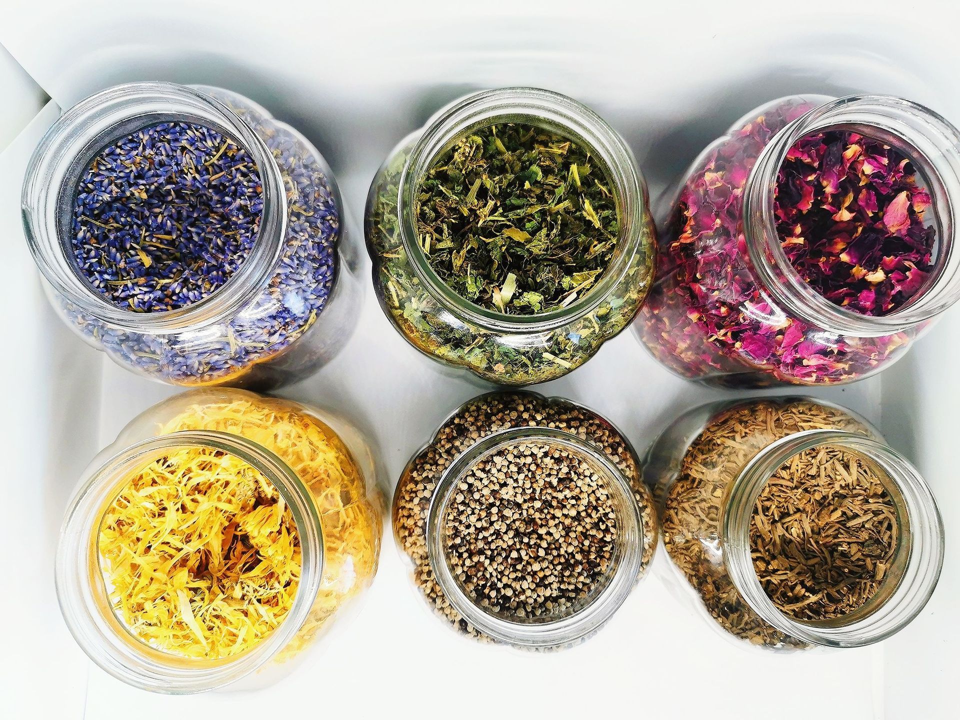 Six jars filled with different types of herbs and spices