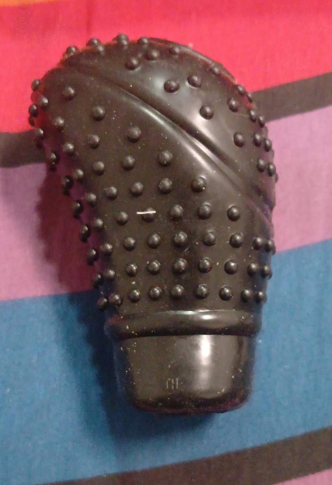 Pomo de palanca de cambios negro con pequeñas protuberancias y costuras rojas alrededor de la base. Interior de coche.